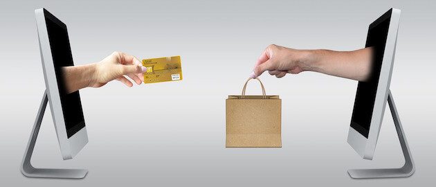 Two hands exchanging payment and product through computer screens.