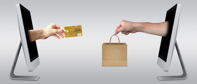 Two hands exchanging payment and product through computer screens.