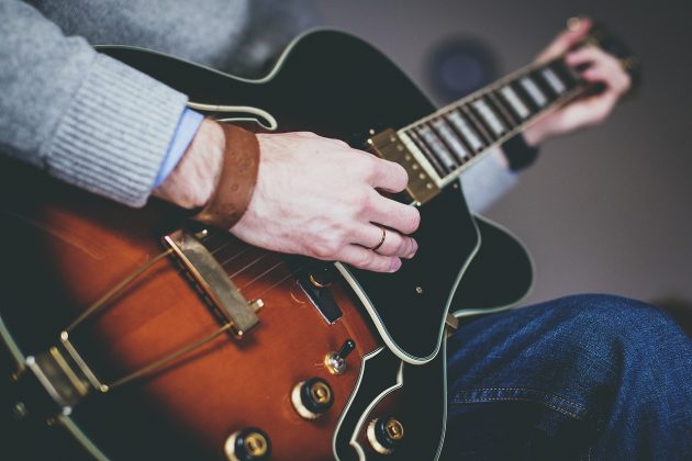 A close up of a man playing an electric guitar.
