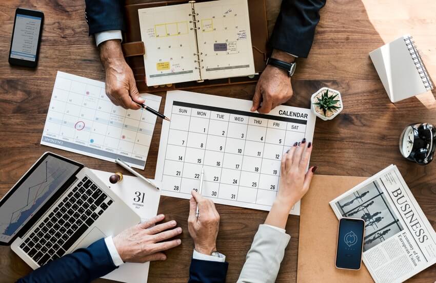 Three people gathered around a calendar.