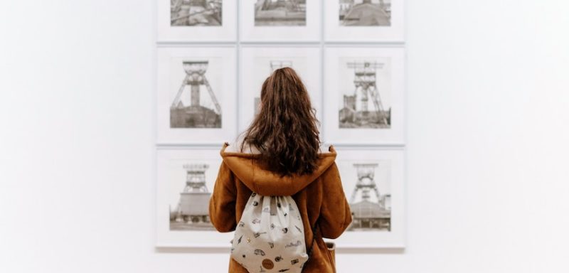 A person looking at a selection of artwork in a gallery.
