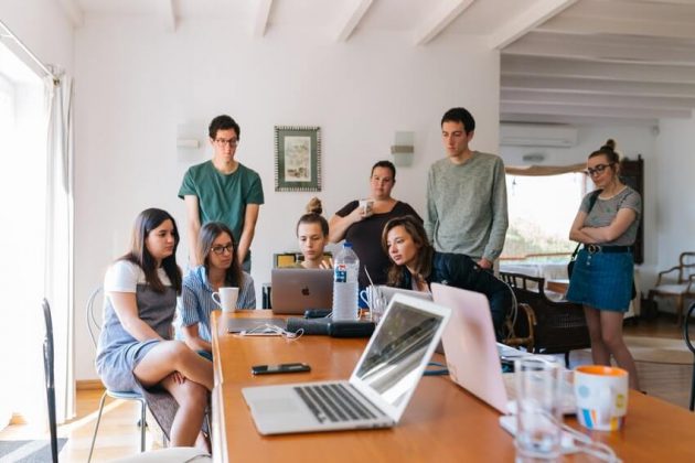 Several people gathered around a laptop.