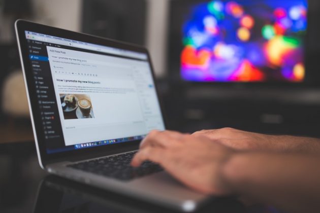 A person writing a blog on a laptop.