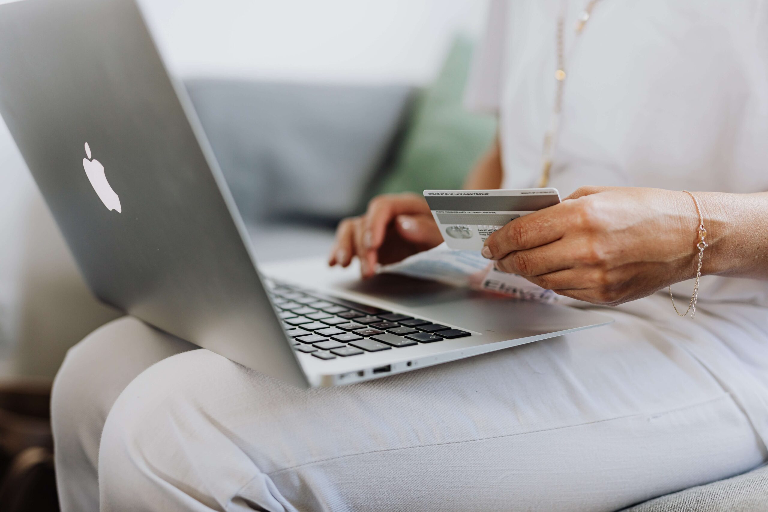 A person using a Macbook and holding a credit card