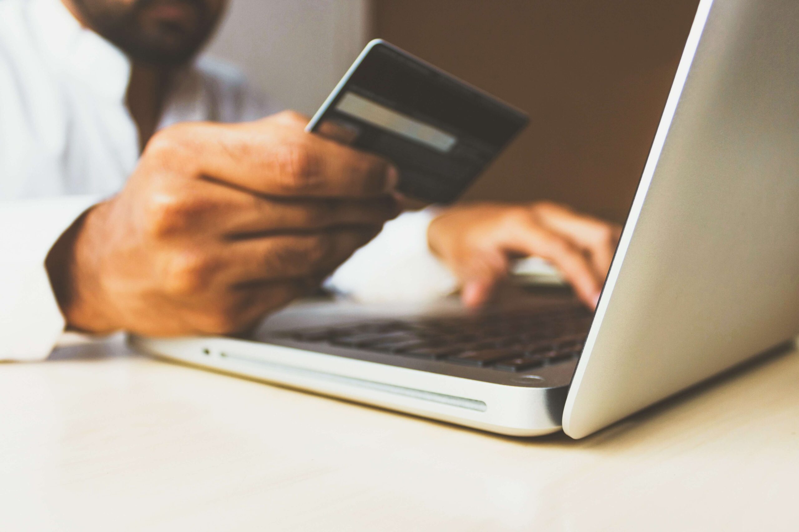 man using a credit card at laptop