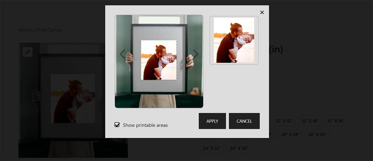 A person holds a framed canvas featuring an image of a man and a child. 