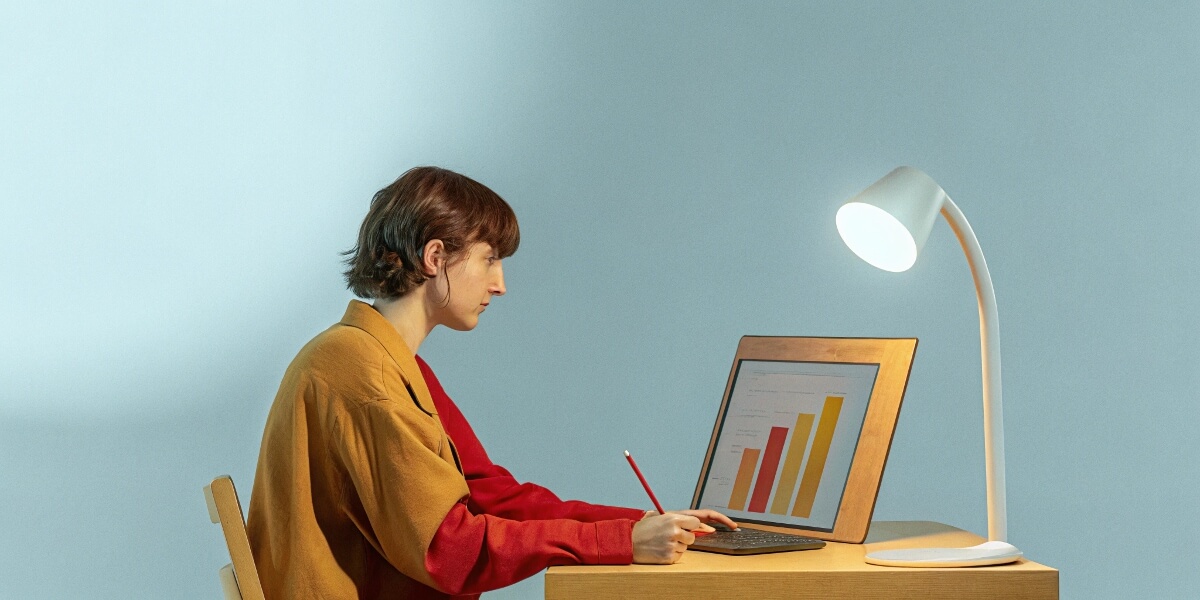 A person sitting alone at their computer with a trend graph on their screen.
